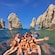 A family posing at the bow of a translucent boat in front of The Arch of Cabo San Lucas